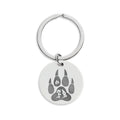 Silver keychain featuring a paw print design on a circular tag, perfect for pet lovers.