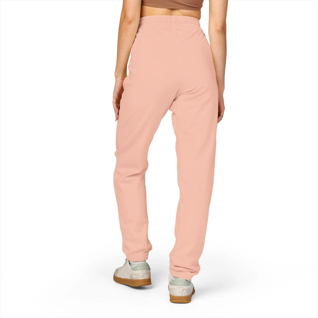 Women’s blush pink joggers made from soft cotton fleece, featuring an elastic waistband and tapered legs.