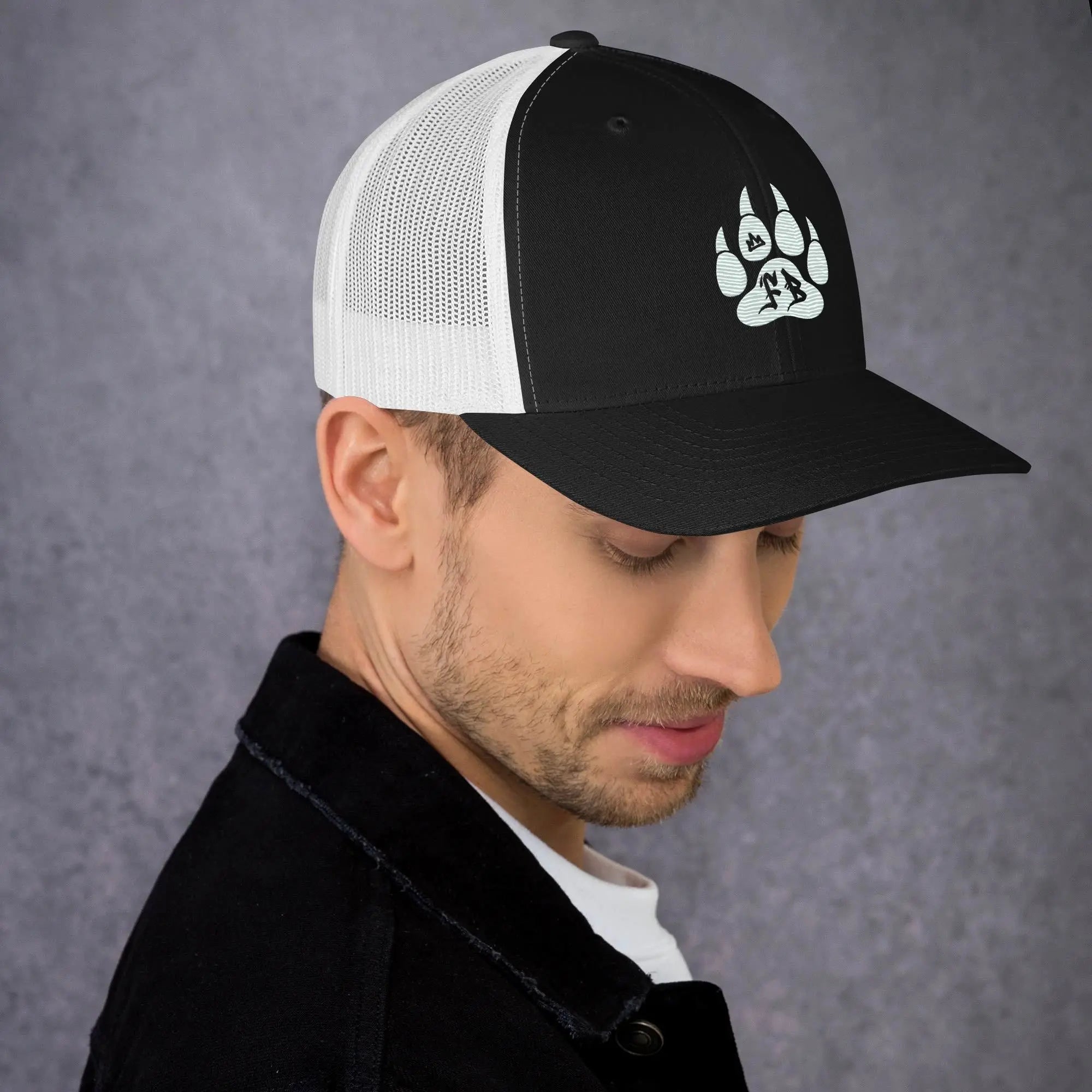 Black and white trucker hat with a paw print design, perfect for outdoor enthusiasts.