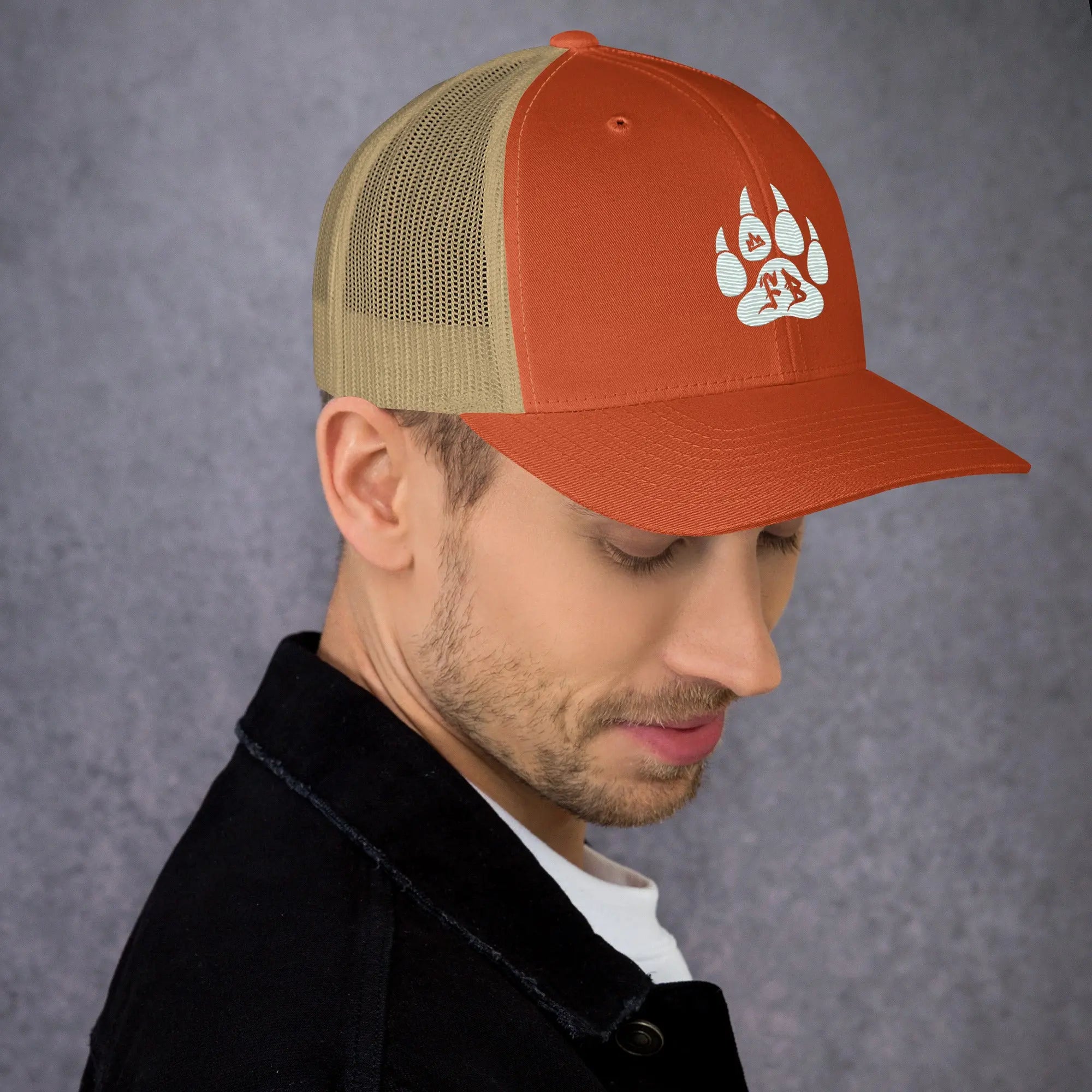 Orange and tan adjustable trucker cap with bear paw print design, perfect for outdoor enthusiasts.